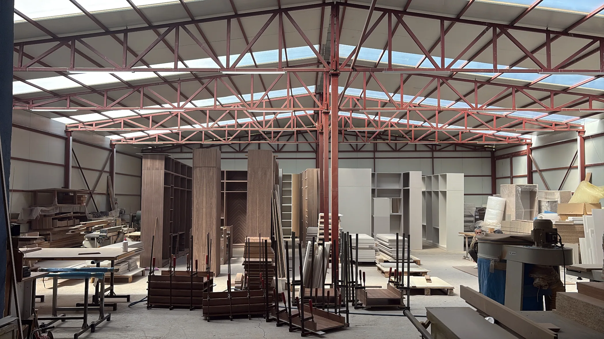 DIM Mobilya workshop floor in Çubuk, Ankara — steel-trussed hall with walnut door sets in production